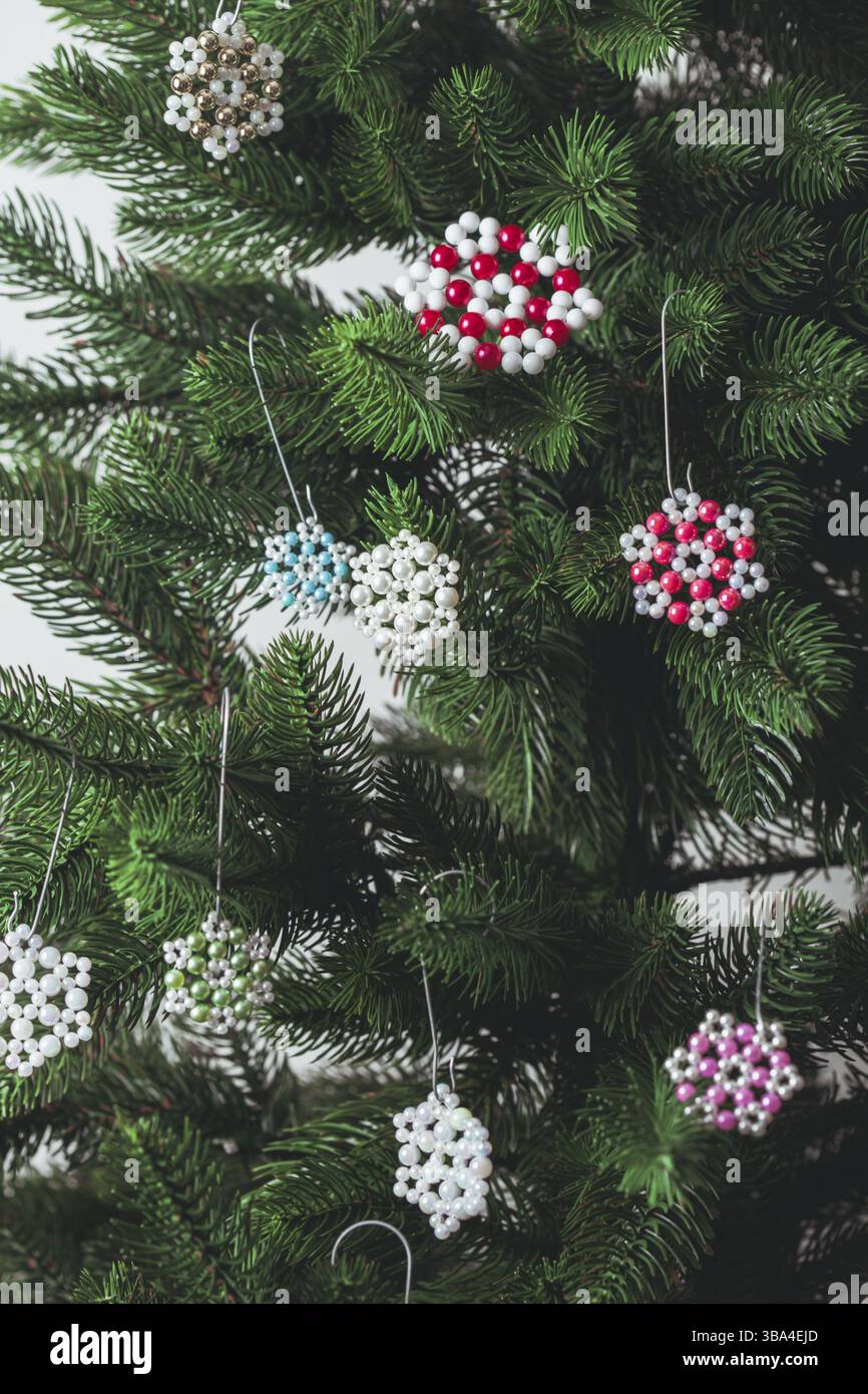 Fiocchi di neve fatti a mano con perline appesi sui rami dell'albero di Natale. Primo piano Foto Stock