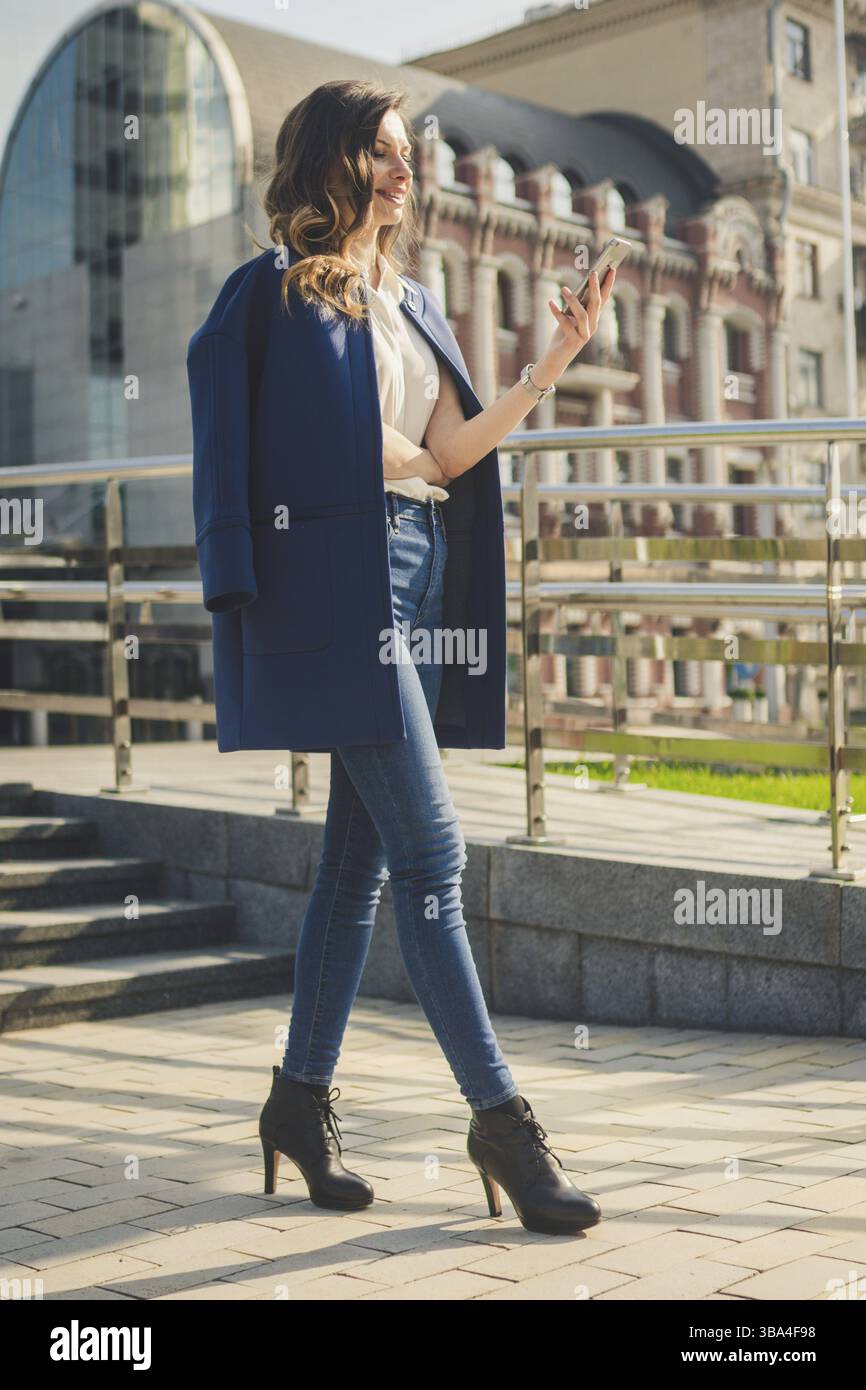 Edifici adibiti a ufficio gente di città in tuta. Imprenditrice caucasica utilizza lo smartphone con la mano. Il concetto di business. Ritratto aziendale elegante donna di moda Foto Stock