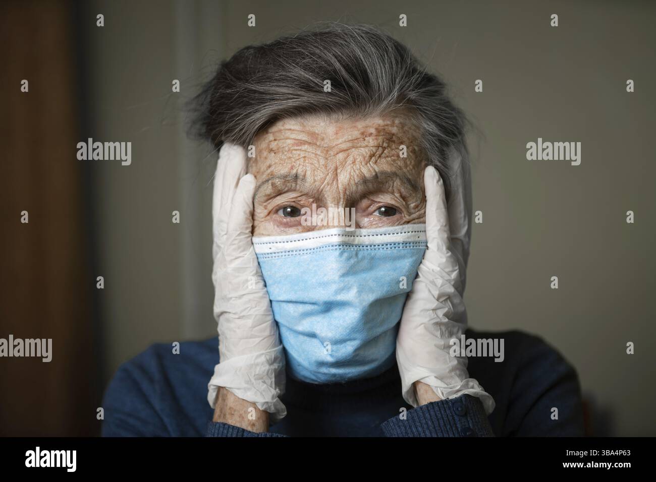 Ritratto di una donna caucasica anziana con rughe, indossando una maschera medica e guanti, l'emozione della fragilità e imprevedibilità dovuta al coronav Foto Stock