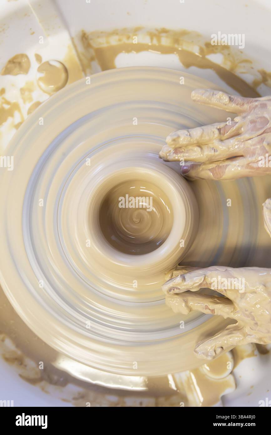 Nahaufnahme der Haende eines Toepfers mit einem Gegenstand auf einem Toepferrad. Arbeiten mit Ton. Argilla-laboratorio. Handwerkstraining Foto Stock