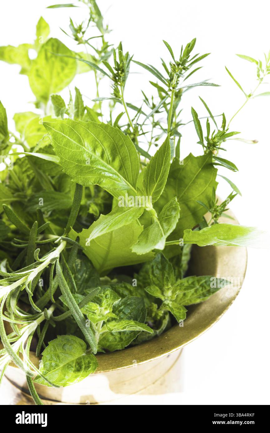 Le erbe fresche nel mortaio di rame sul tavolo Foto Stock