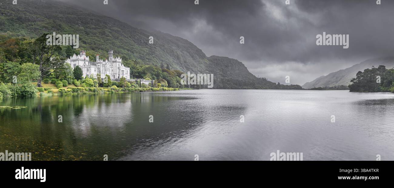 Kylemore Abbey, bellissimo castello bianco ai piedi di una montagna con un suggestivo cielo scuro sullo sfondo. Monastero benedettino Connemara Galway, Irlanda Foto Stock