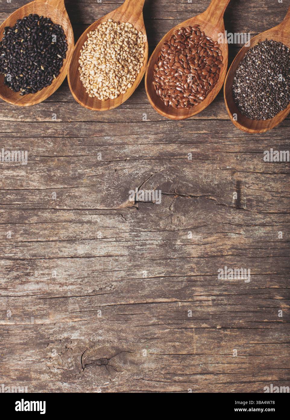 Semi di Chia e lino, sesamo bianco e nero in cucchiai di legno Foto Stock