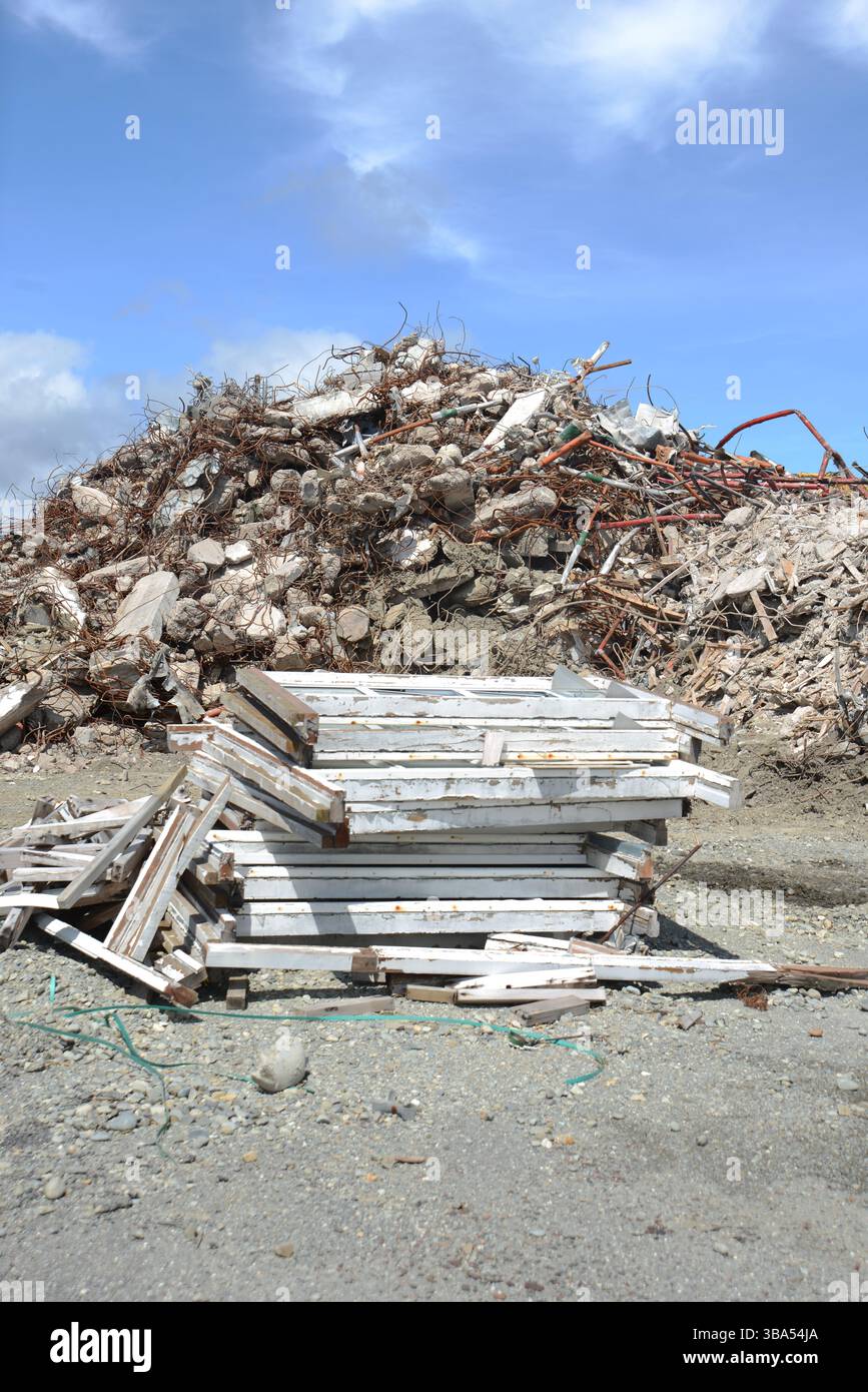 Alcuni telai per finestre in legno impilati accanto alle macerie di un sito di demolizione Foto Stock
