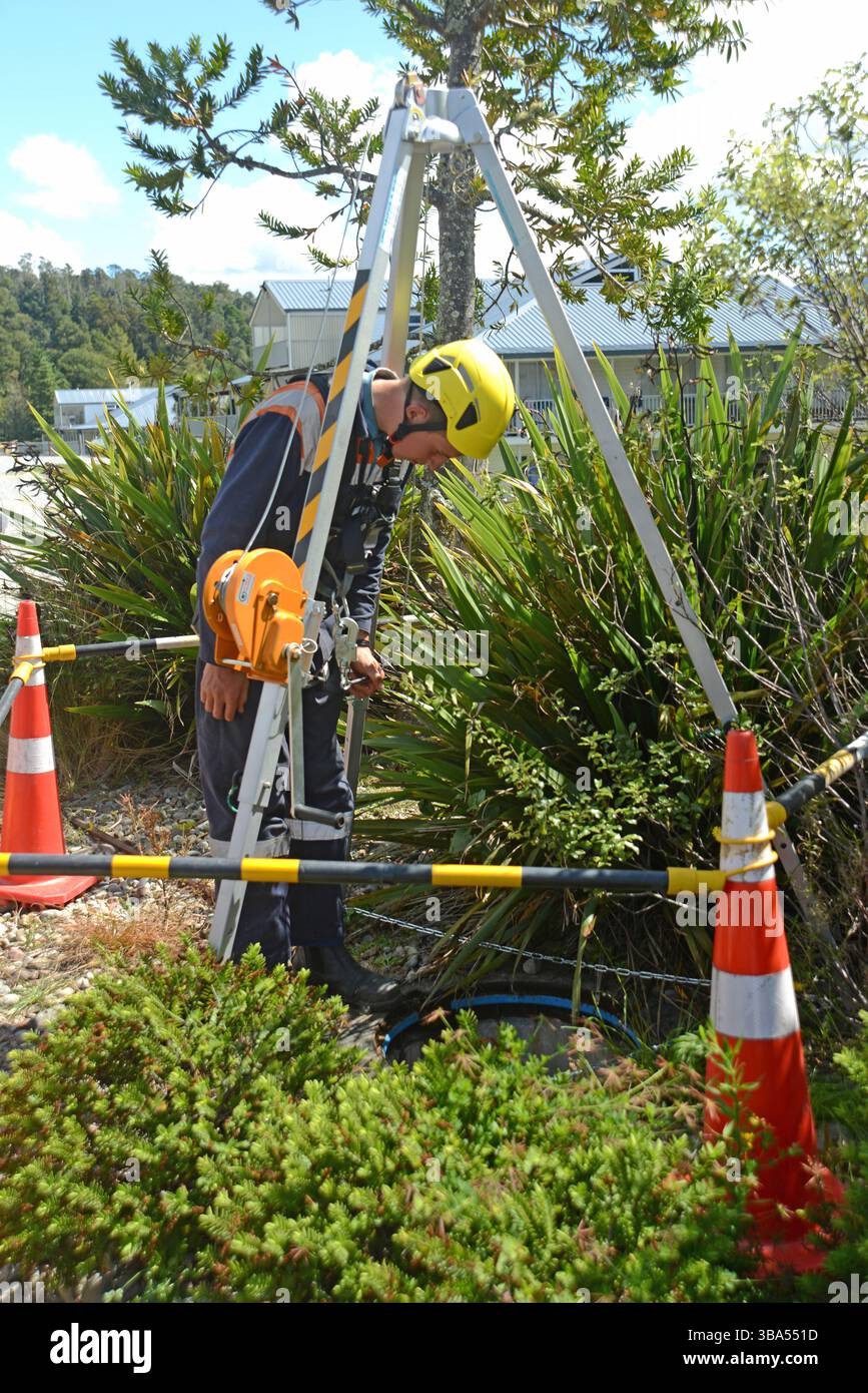 Un apprendista idraulico entra in uno spazio ristretto per un esercizio di formazione in uno scarico di acqua piovana in una proprietà commerciale Foto Stock
