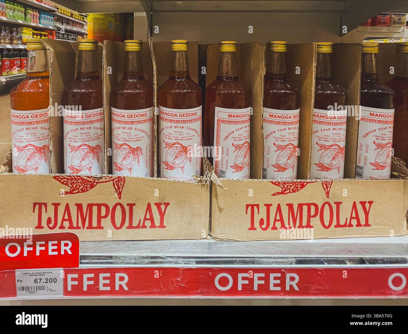 Balikpapan, Indonesia – 11 maggio 2025. Le bottiglie di sciroppo di mango Tjampolay sono disposte in modo ordinato su uno scaffale con cartellini dei prezzi promozionali in un supermercato locale. Foto Stock