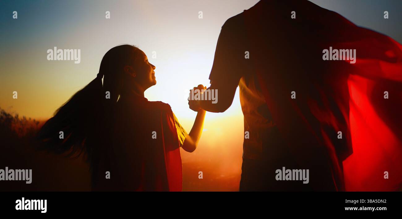 Famiglia felice amorevole. Padre e sua figlia giocano all'aperto. Daddy e la sua bambina in costumi di un Supereroe. Foto Stock