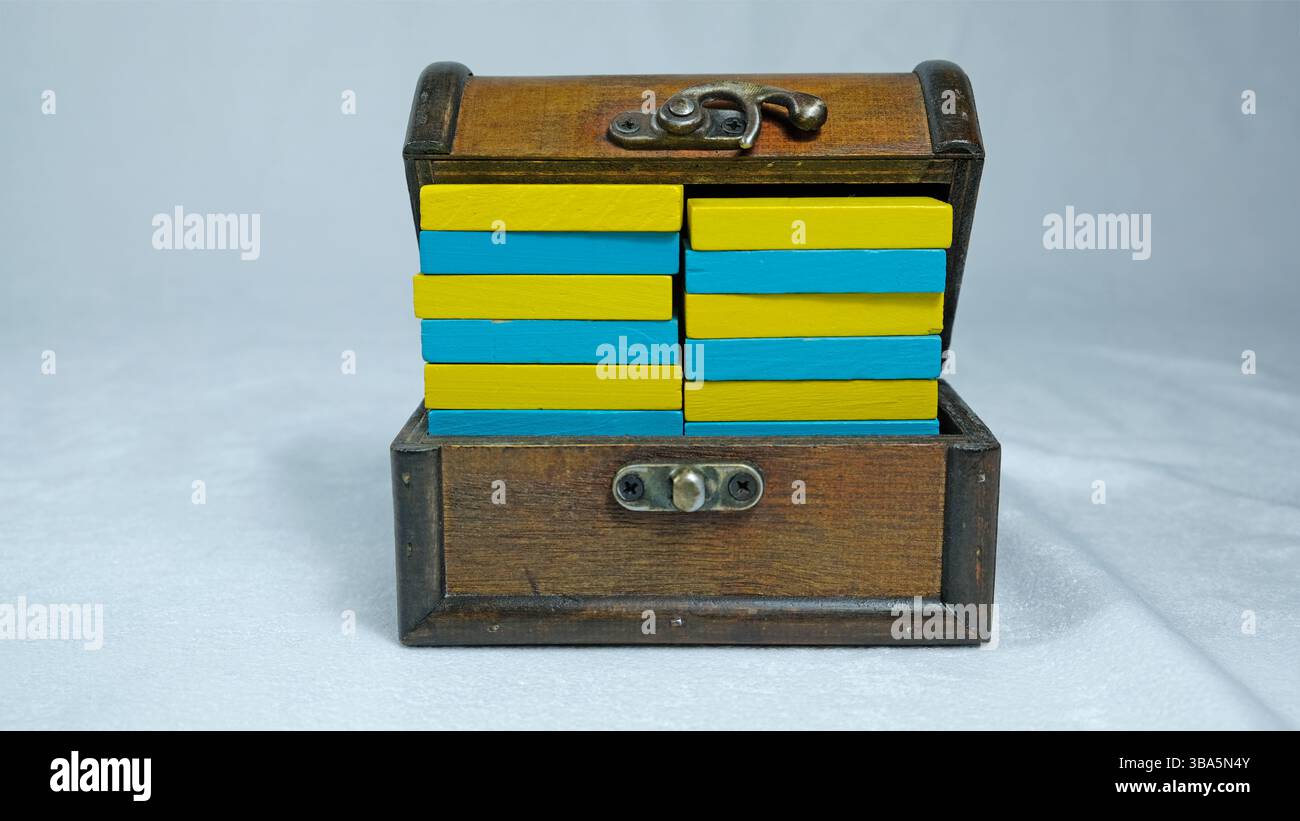 Scatola in legno decorativa retrò riempita con pezzi a cupola in legno giallo e blu ordinati Foto Stock