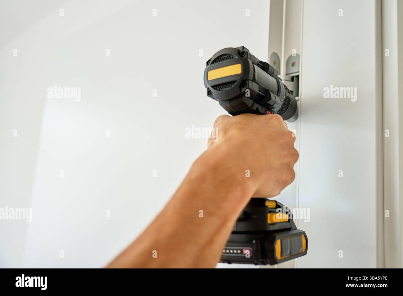 Avvitare la vite con un cacciavite, assemblando mobili. Primo piano dell'installazione dello sportello con trapano a batteria Foto Stock
