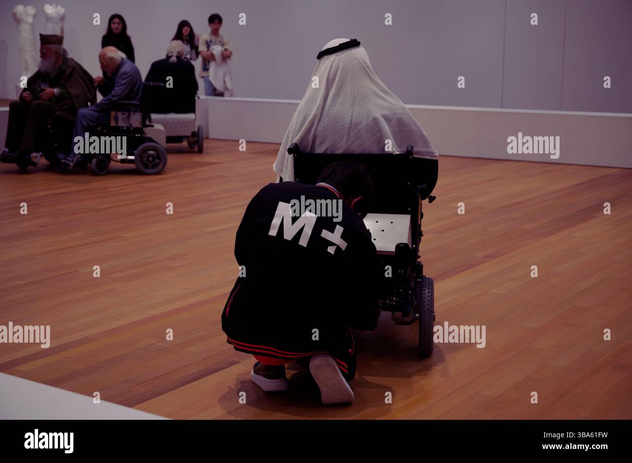 Il membro del personale del museo adatta una sedia a rotelle nell'installazione "Old Persons Home" di Sun Yuan e Peng Yu presso il M+ Museum Foto Stock