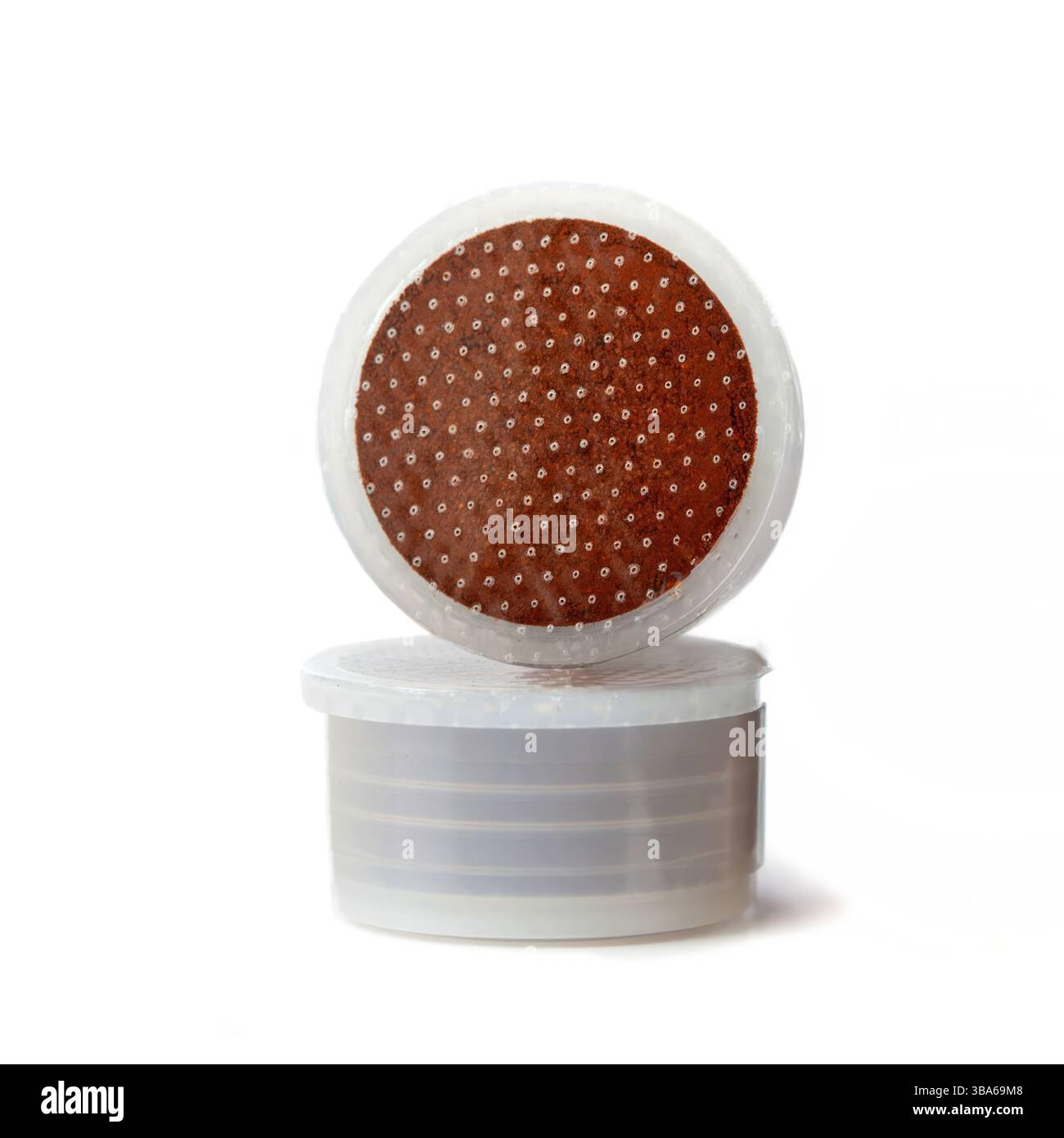 Due cialde di caffè bilanciate su sfondo bianco, creano un'interessante composizione di forme e colori, perfette per rappresentare il concetto di pausa caffè o dipendenza da caffeina Foto Stock