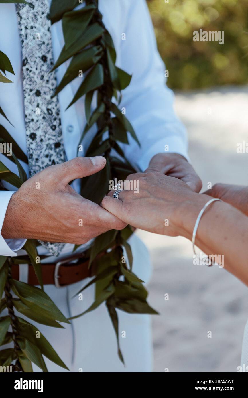 Dettagli sposi in possesso di leis hawaiano in spiaggia Foto Stock