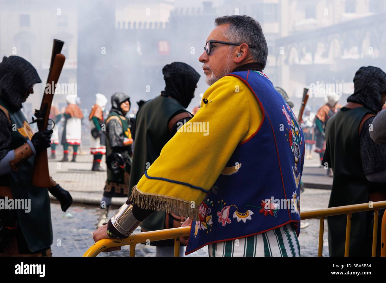 Alcoy, Spagna, 05-05-2025: Membro della compagnia Ligeros che guarda la guerra degli archibugi appoggiandosi contro una recinzione Foto Stock