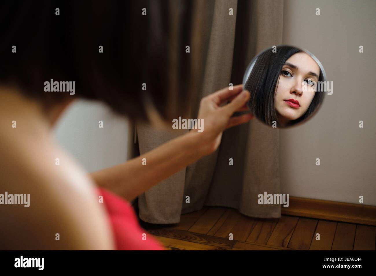 La donna ammira il riflesso in un piccolo specchio all'interno Foto Stock