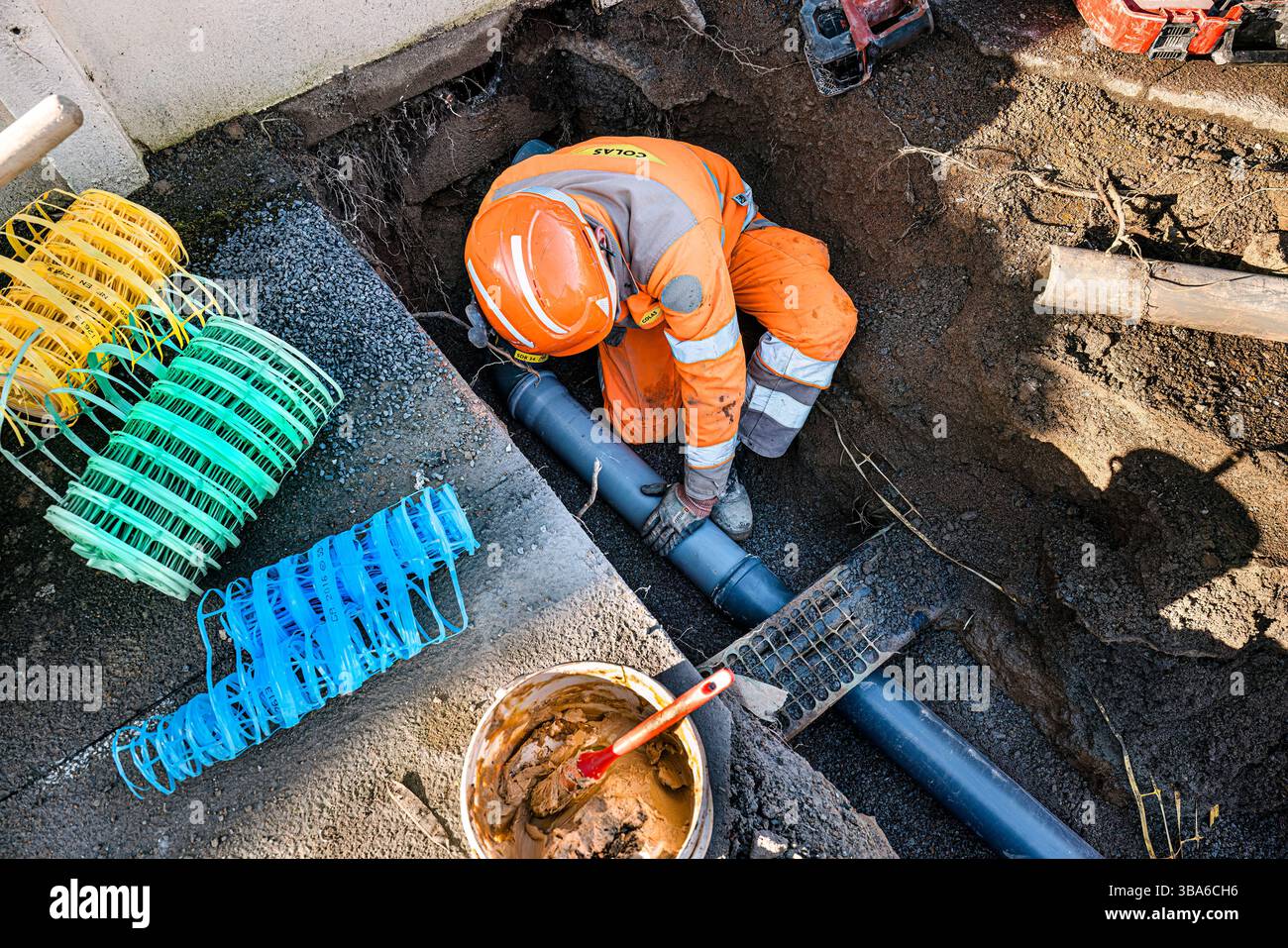 Edilizia e ingegneria civile: Strato di tubazioni in un cantiere. Un posatubi è un commerciante esperto che posa tubi, come per le fognature per le tempeste, sani Foto Stock