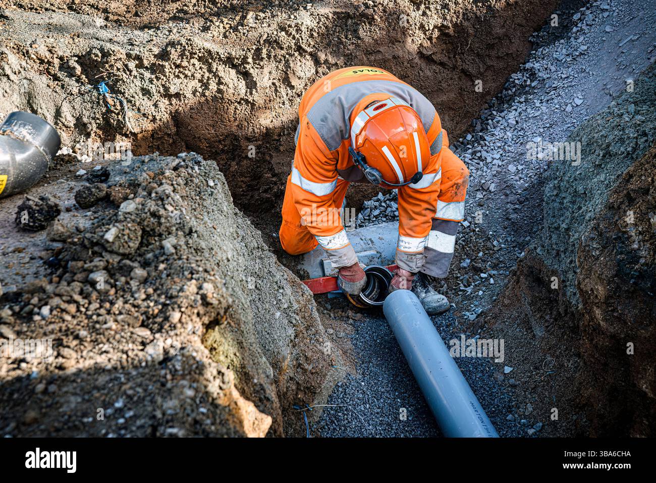 Edilizia e ingegneria civile: Strato di tubazioni in un cantiere. Un posatubi è un commerciante esperto che posa tubi, come per le fognature per le tempeste, sani Foto Stock