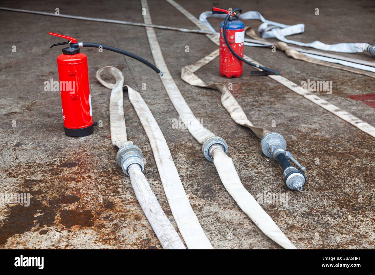 Cilindro dell'estintore rosso con tubi flessibili antincendio non avvolti. Foto Stock