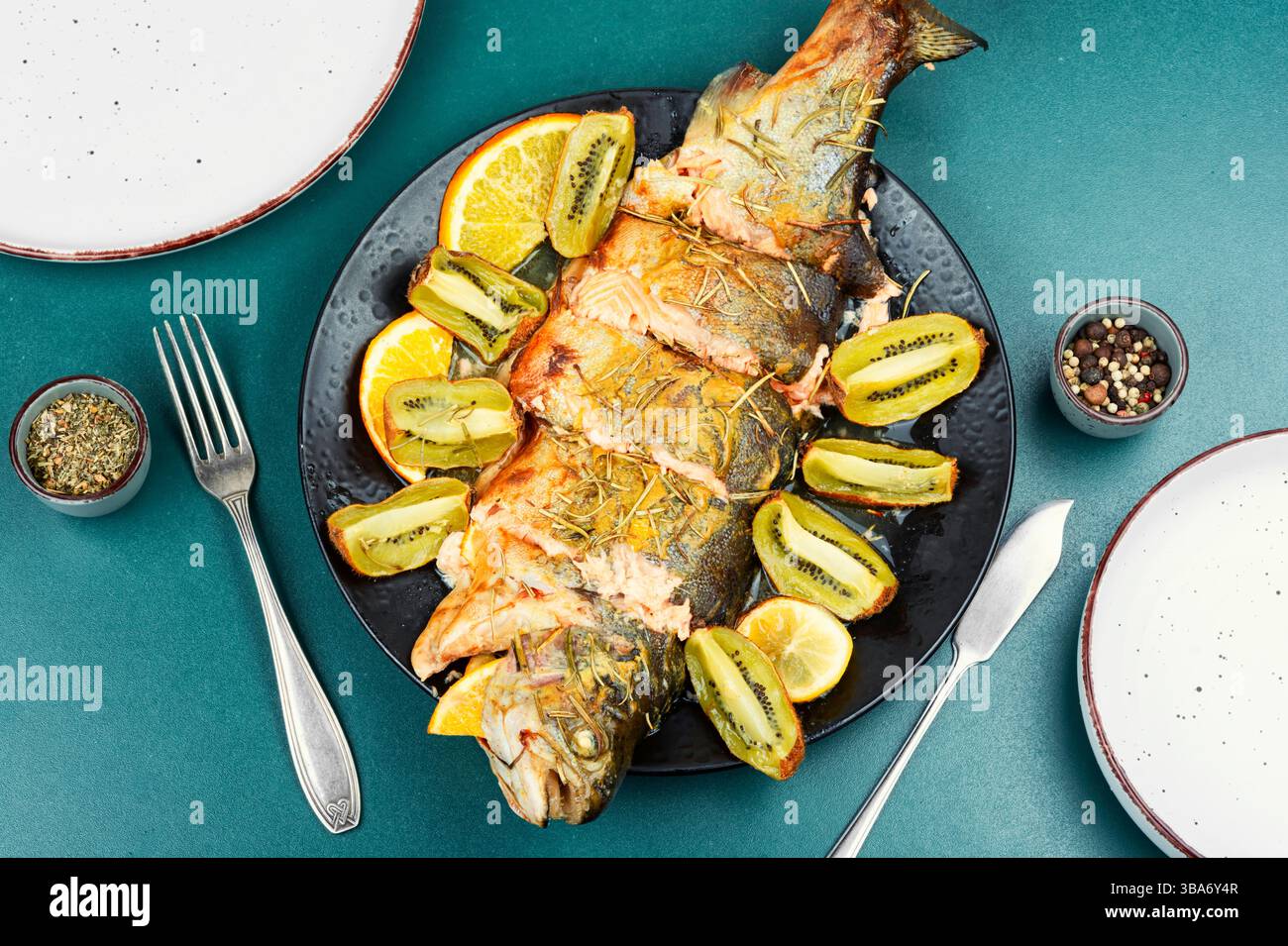Delizioso pesce di trota al forno con kiwi e arancia. Foto Stock