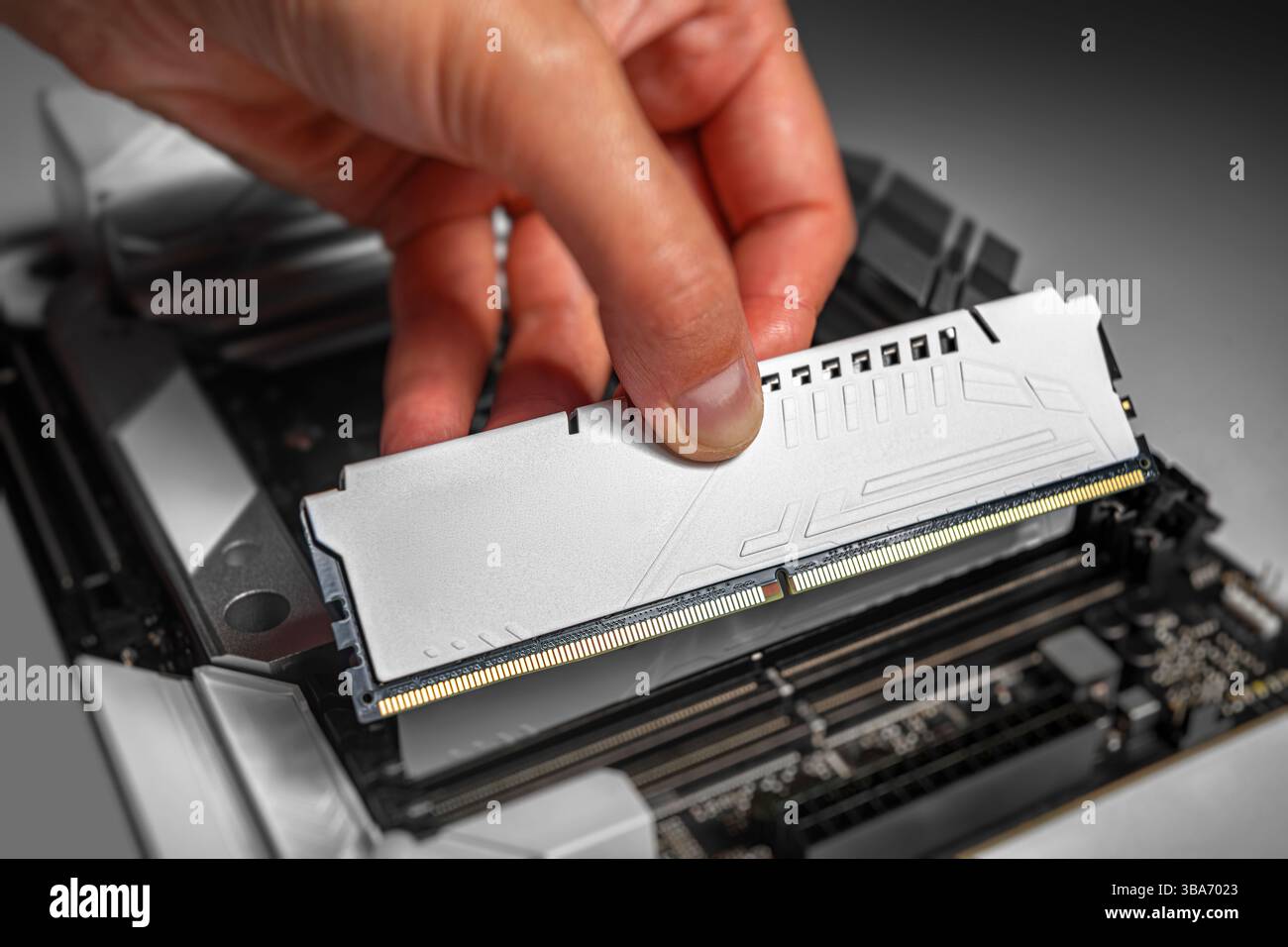 Una persona sta installando un modulo di memoria DDR bianco in una scheda madre per sistemi desktop Foto Stock