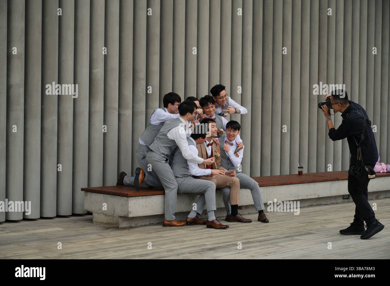 I Groomsmen si riuniscono intorno allo sposo per una divertente foto di gruppo nel West Kowloon Art Park Foto Stock