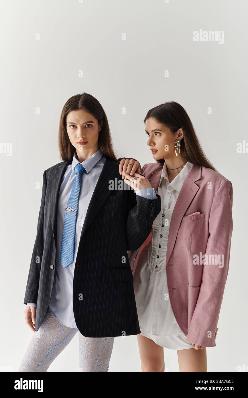 Due eleganti gemelle sfoggiano il loro look unico in abiti alla moda. Foto Stock
