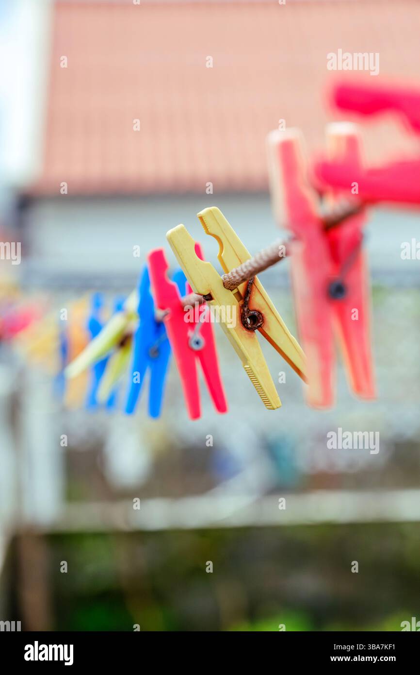 Clothespin in plastica colorata appesi su una Clothesline. Illustra le attività quotidiane di lavanderia e i vivaci articoli per la casa. Foto Stock
