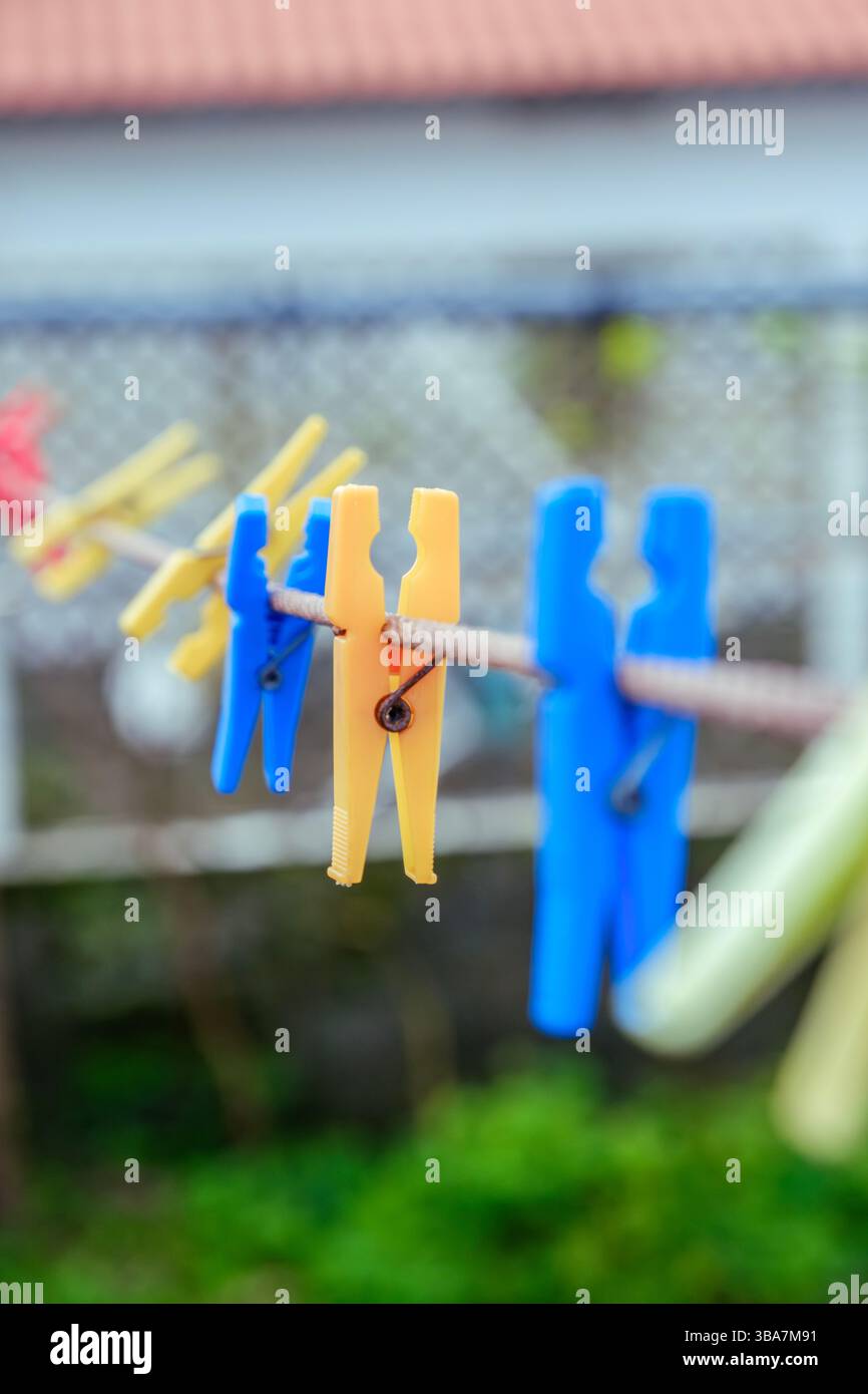 Clothespin in plastica colorata appesi su una Clothesline. Illustra le attività quotidiane di lavanderia e i vivaci articoli per la casa. Foto Stock