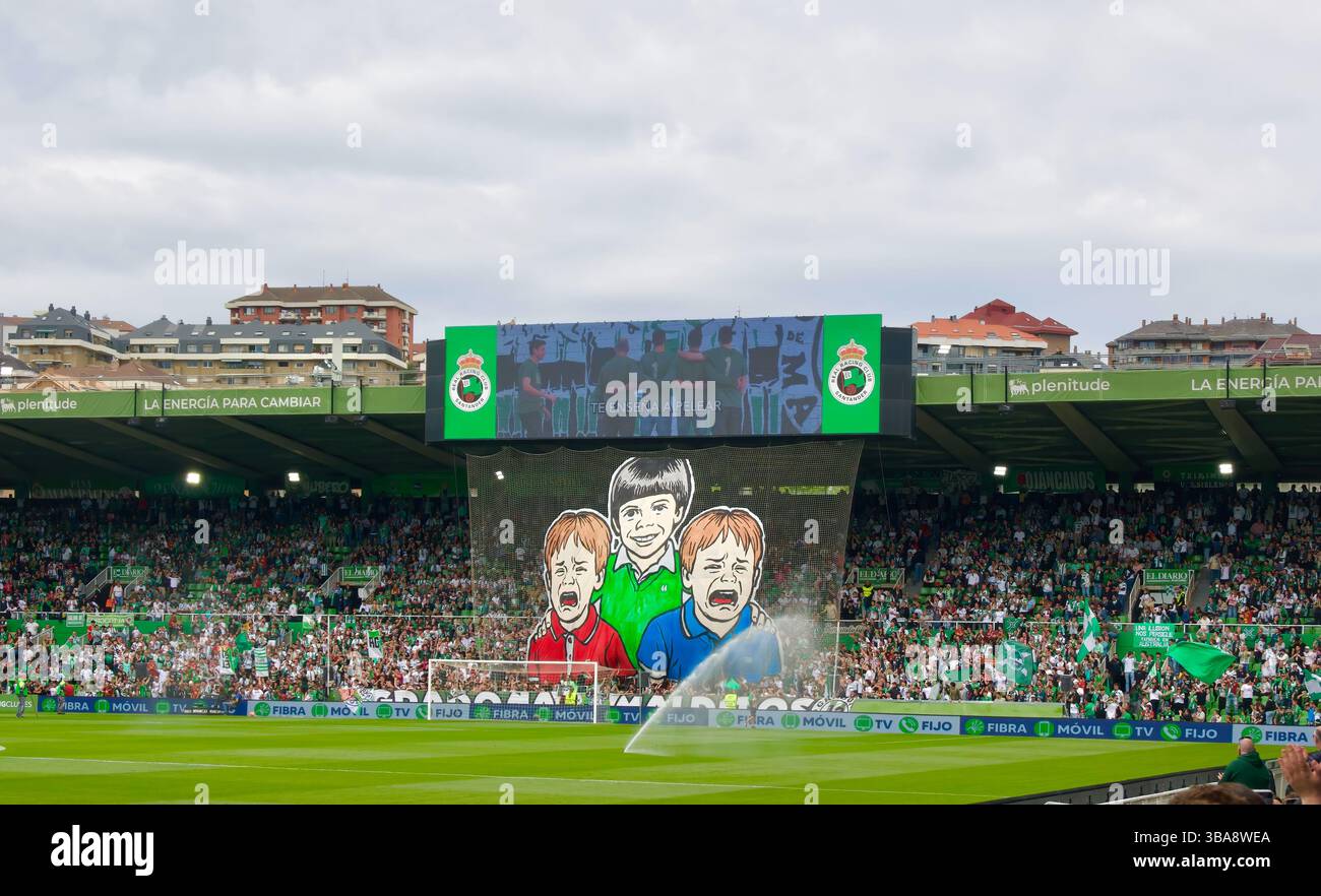 Sorridente bambino Racing con pianto Oviedo e Sporting de Gijón bambini su un enorme striscione con il numero di anni in prima divisione sulle loro camicie Foto Stock