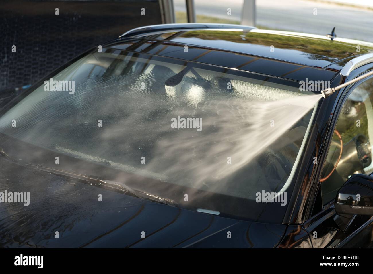 Una persona sta lavando un'auto nera con un tubo dell'acqua ad alta pressione Foto Stock