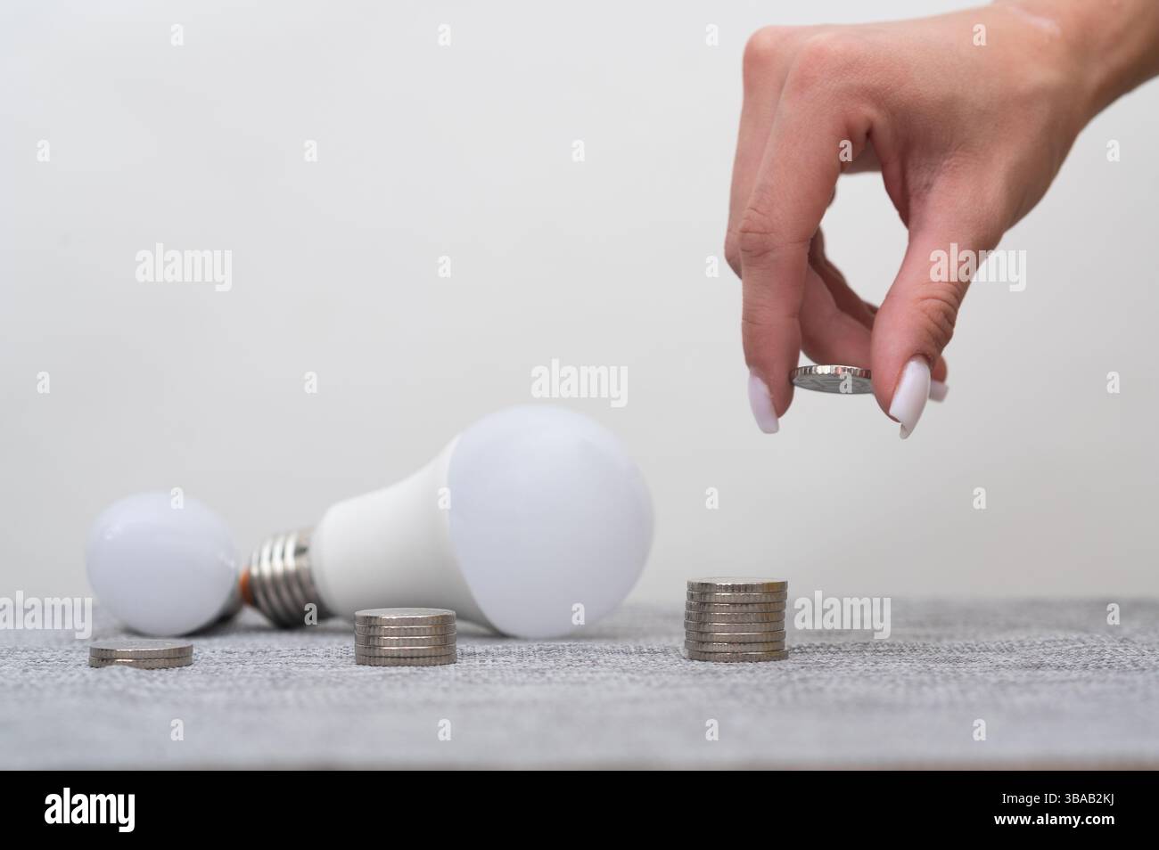 Donna che posiziona le monete in pile. Ci sono lampade a LED nelle vicinanze. Le monete riflettono le abitudini personali di budget, un tranquillo controllo finanziario. risparmio su eletti Foto Stock