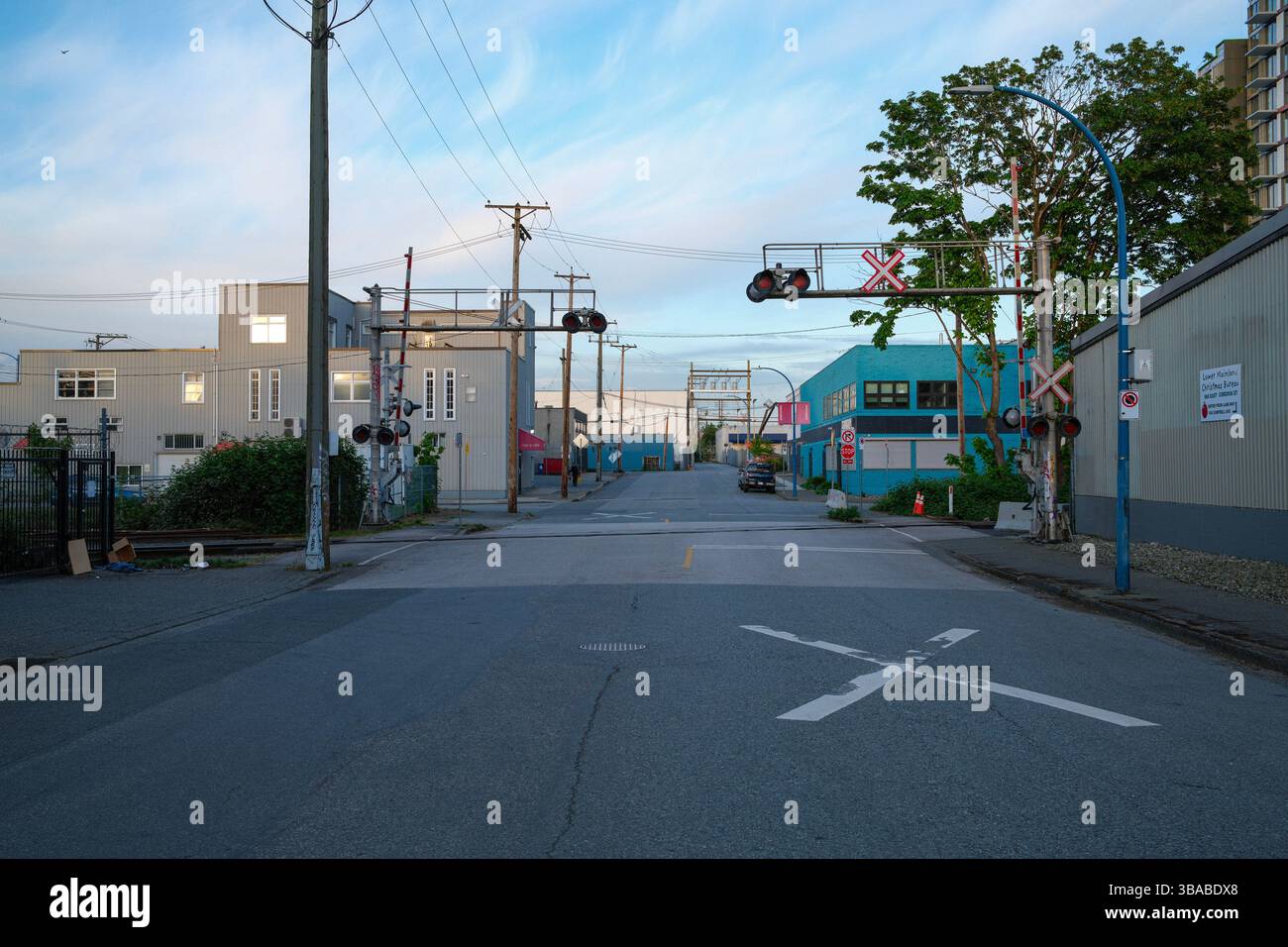 Una ferrovia che attraversa una strada vuota a East Vancouver, British Columbia. Foto Stock
