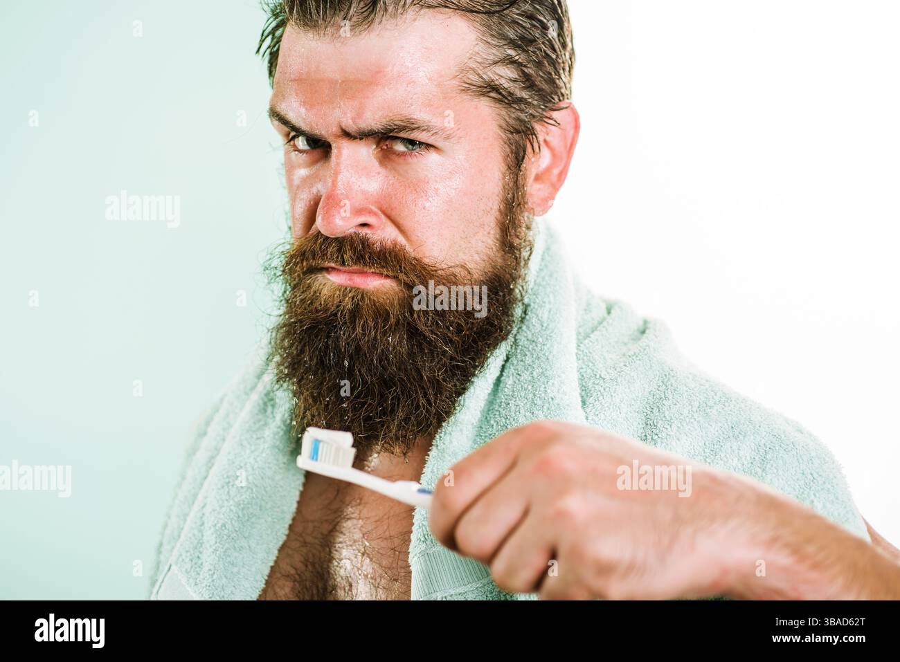 Uomo barbuto che spazzola i denti in bagno. Routine mattutina. Uomo serio con spazzolino da denti. Bel ragazzo che pulisce i denti. Denti e gengive sani. L'uomo sbianca Foto Stock