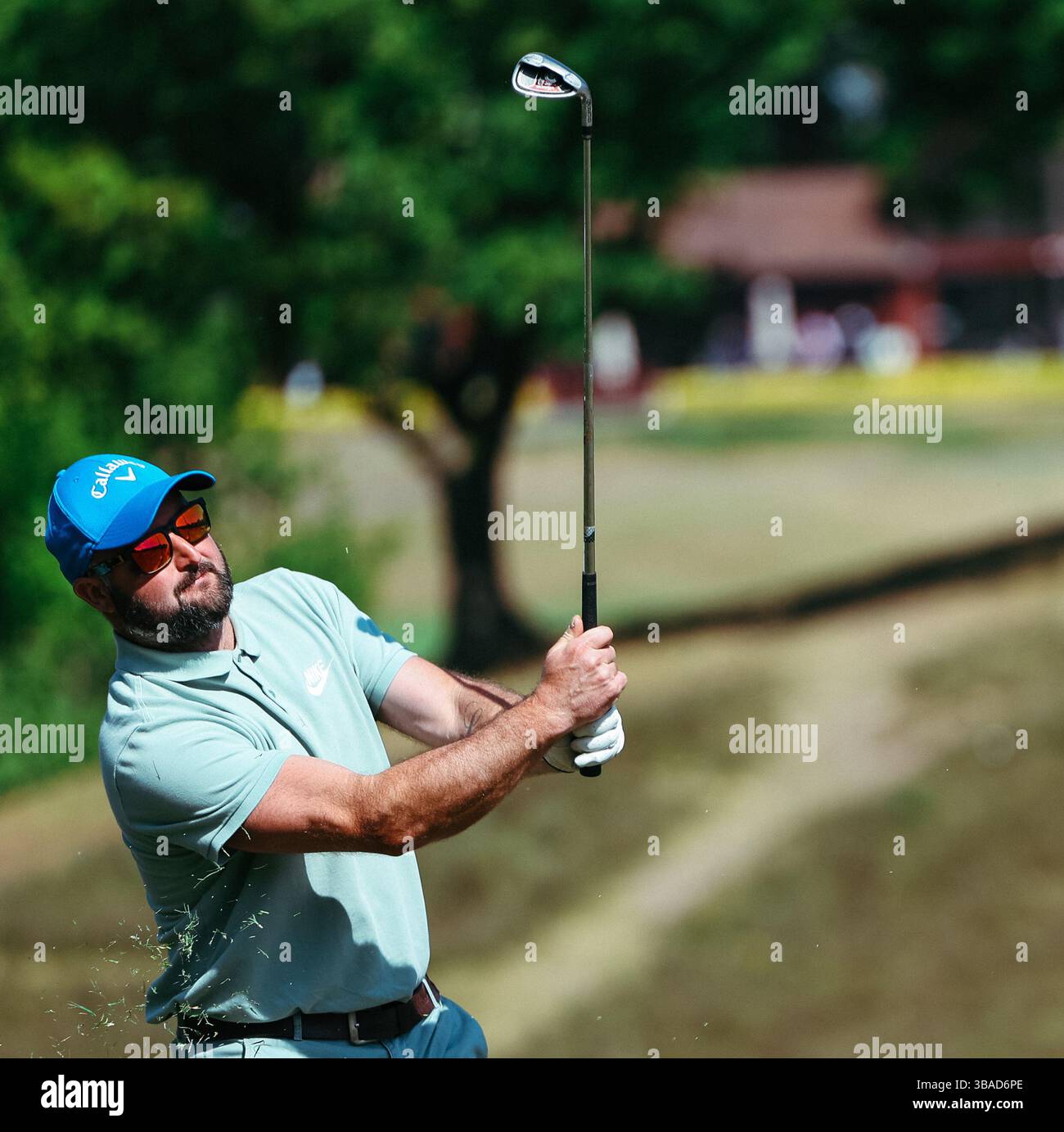 Golfista maschile con cappello e occhiali da sole che scatta una foto sul fairway Foto Stock
