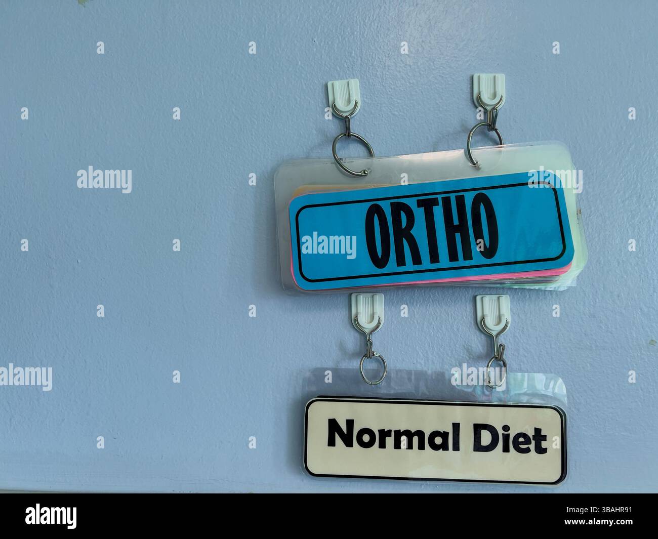 Cartelli ospedalieri appesi ai ganci, che indicano il reparto di ortografia e la dieta normale per i pazienti. - Immagine stock catturata con smartphone