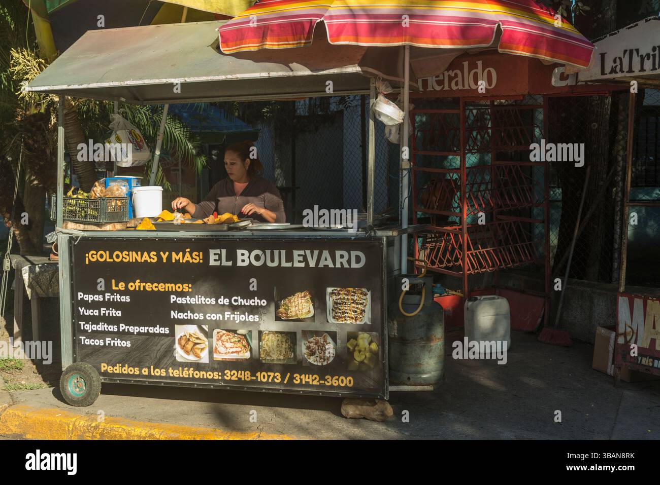 Stallo di cibo. Donna che prepara un fast food centroamericano fritto locale. Honduras. Foto Stock