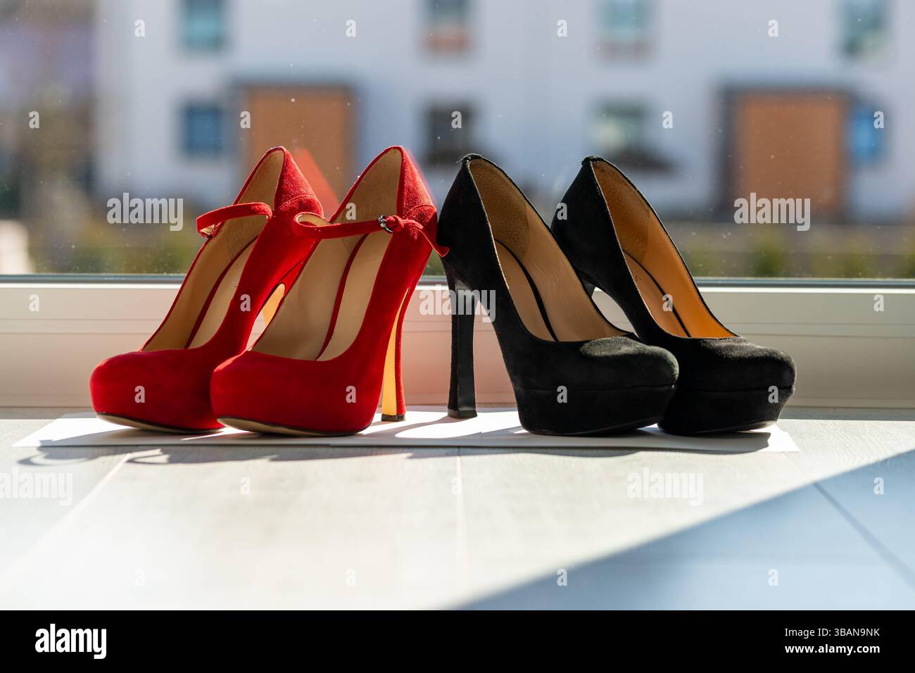 2 paia di décolleté da donna in fila sul pavimento davanti a una finestra Foto Stock