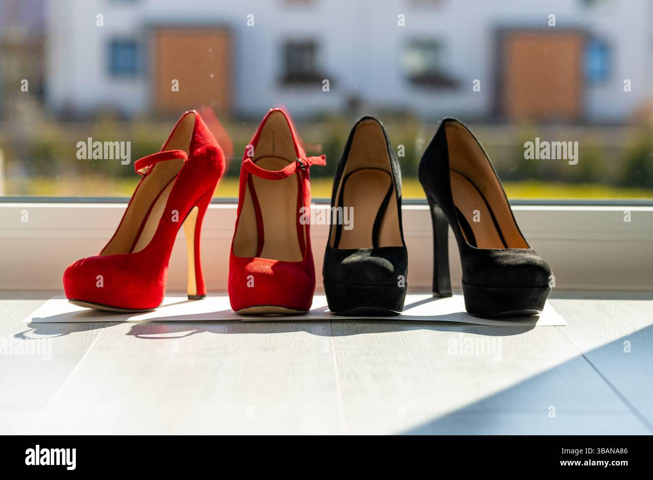 2 paia di décolleté da donna in fila sul pavimento davanti a una finestra Foto Stock