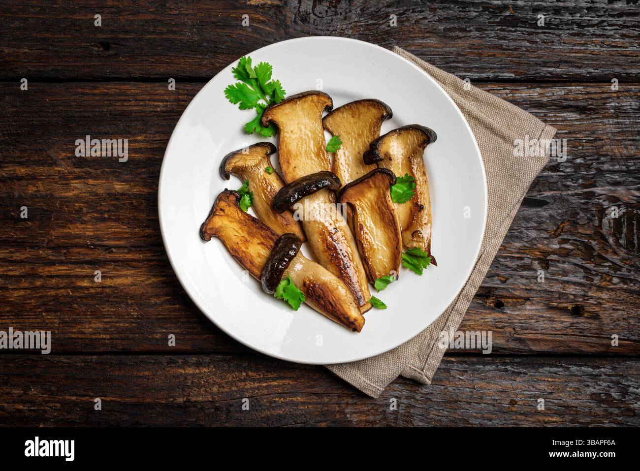 King Oyster Mushroom Steak su sfondo di legno scuro, vista dall'alto. Cibo vegetariano vegano sano, fonte di proteine vegetali, funghi Eryngii Foto Stock