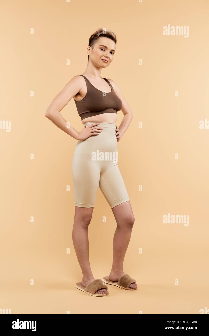 Una donna sicura di sé posa magnificamente nell'abbigliamento sportivo, mostrando la positività del corpo. Foto Stock