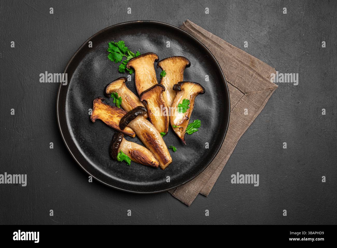 Bistecca di funghi king Oyster su sfondo nero, vista dall'alto, spazio fotocopie. Cibo vegetariano vegano sano, fonte di proteine vegetali, funghi Eryngii Foto Stock