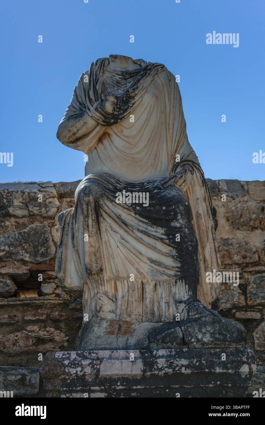 Statua senza testa seduto dal bagno di varius a Efeso, drappeggiata in abiti di marmo, simboleggia la classica cultura romana del bagno. Foto Stock