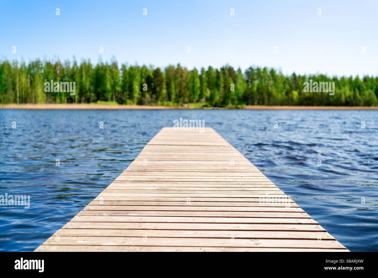 Attracco e sfondo lago. Finlandia in estate. Acqua, foresta e cielo. Molo di legno nel fiume. Alberi sfocati. Blu e verde. Splendida natura finlandese. Foto Stock