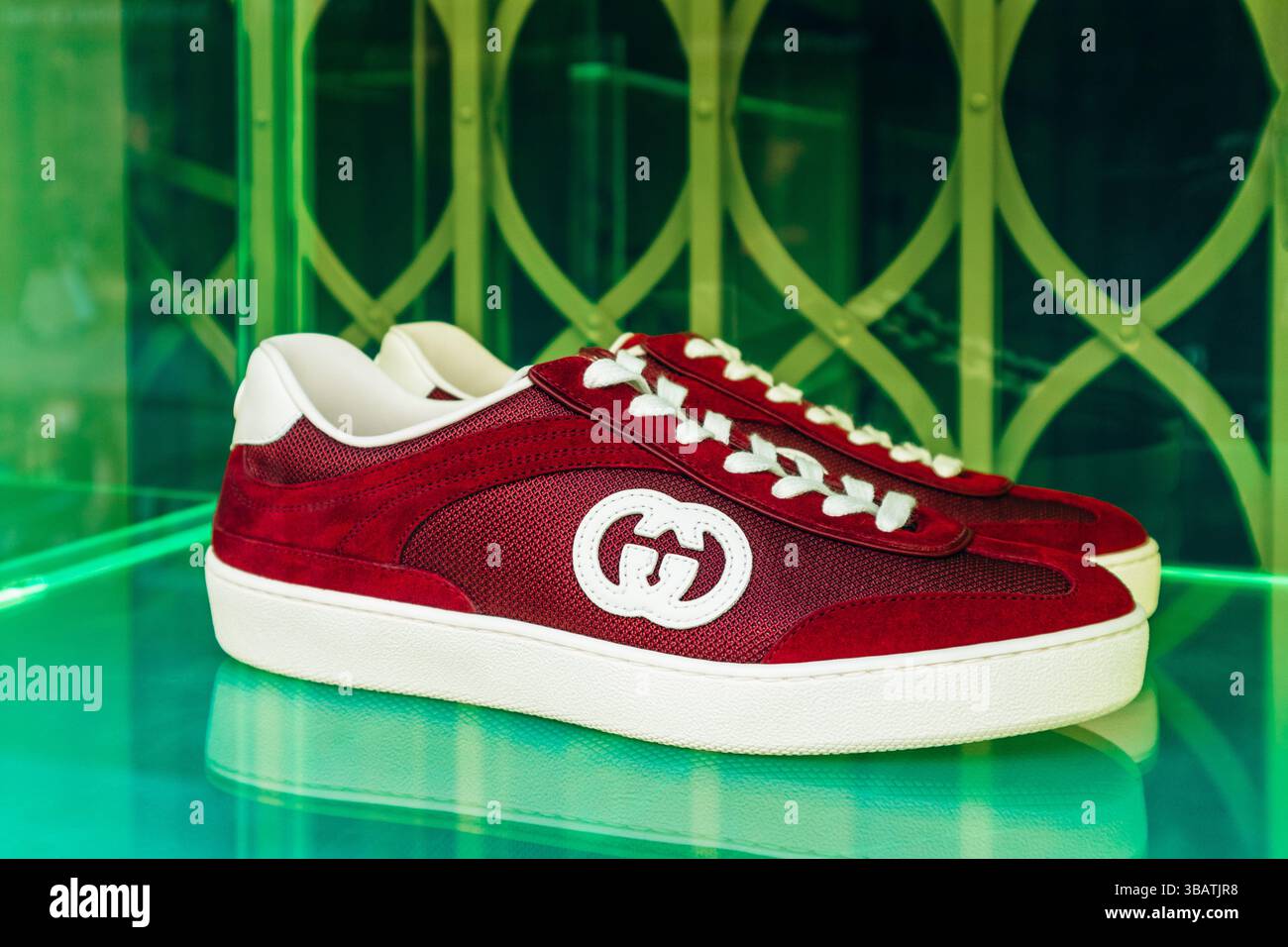 Parigi, Francia - 23 febbraio 2025: Boutique Gucci su rue Saint-Honoré, primo piano di sneakers in camoscio rosso e mesh con logo GG bianco, calzature di lusso displ Foto Stock