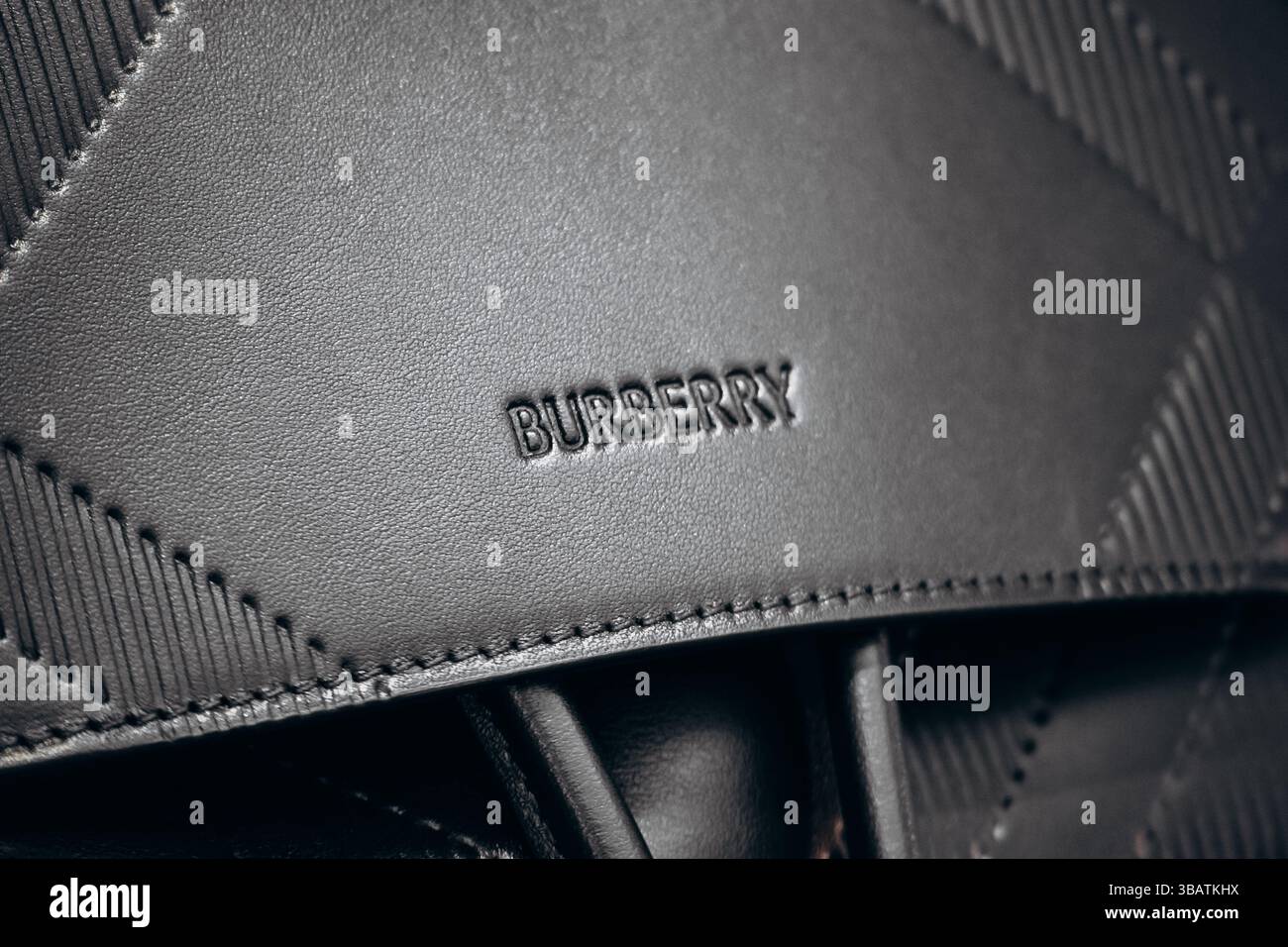 Parigi, Francia - 23 febbraio 2025: Primo piano della borsa in pelle nera Burberry con logo in rilievo e motivo a quadri Foto Stock