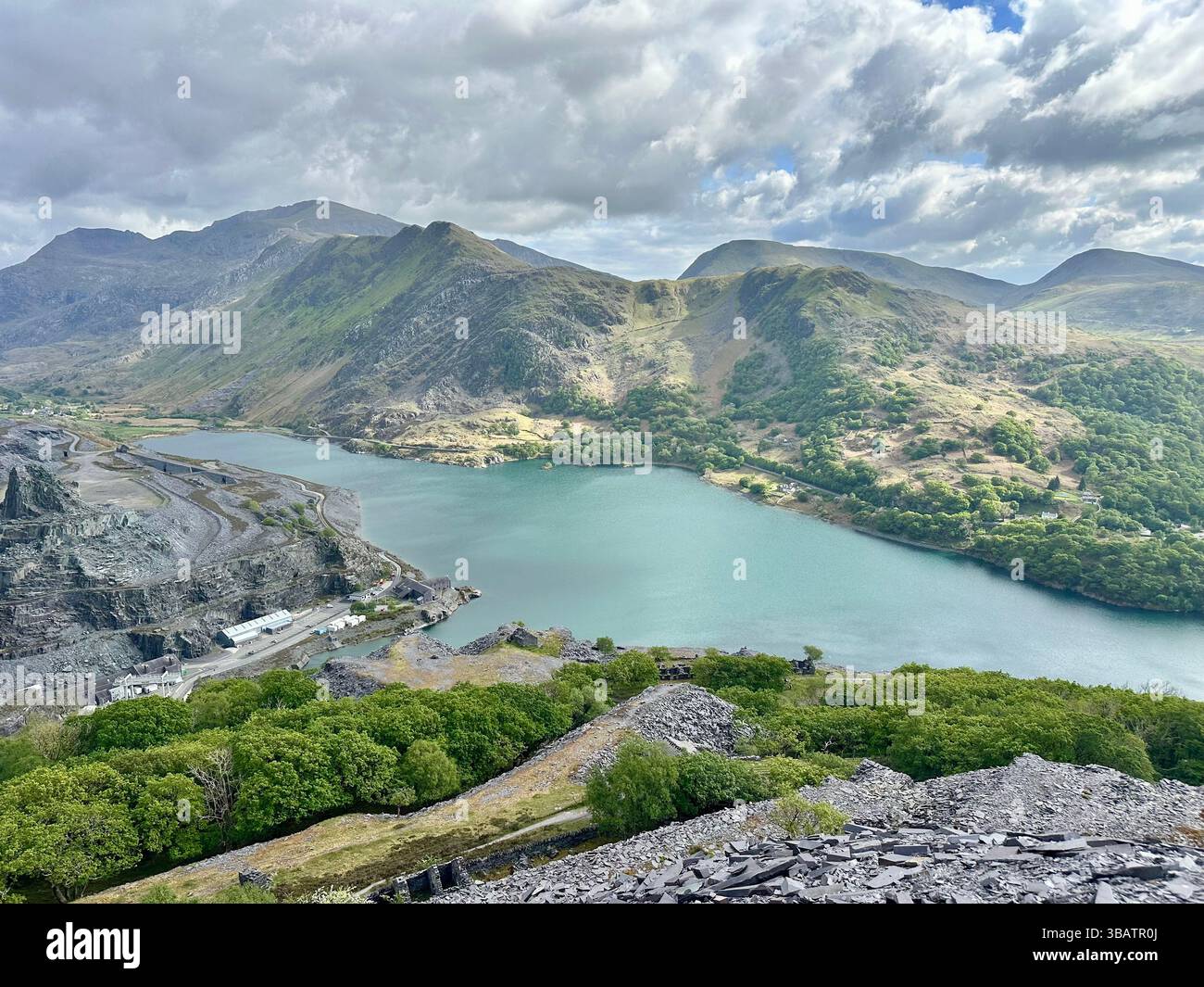 Vista panoramica sopraelevata dalla cava Dinorwic che si affaccia su Llyn Paris con il suggestivo paesaggio montano di Snowdonia sullo sfondo. Giorno luminoso. - Immagine stock catturata con smartphone