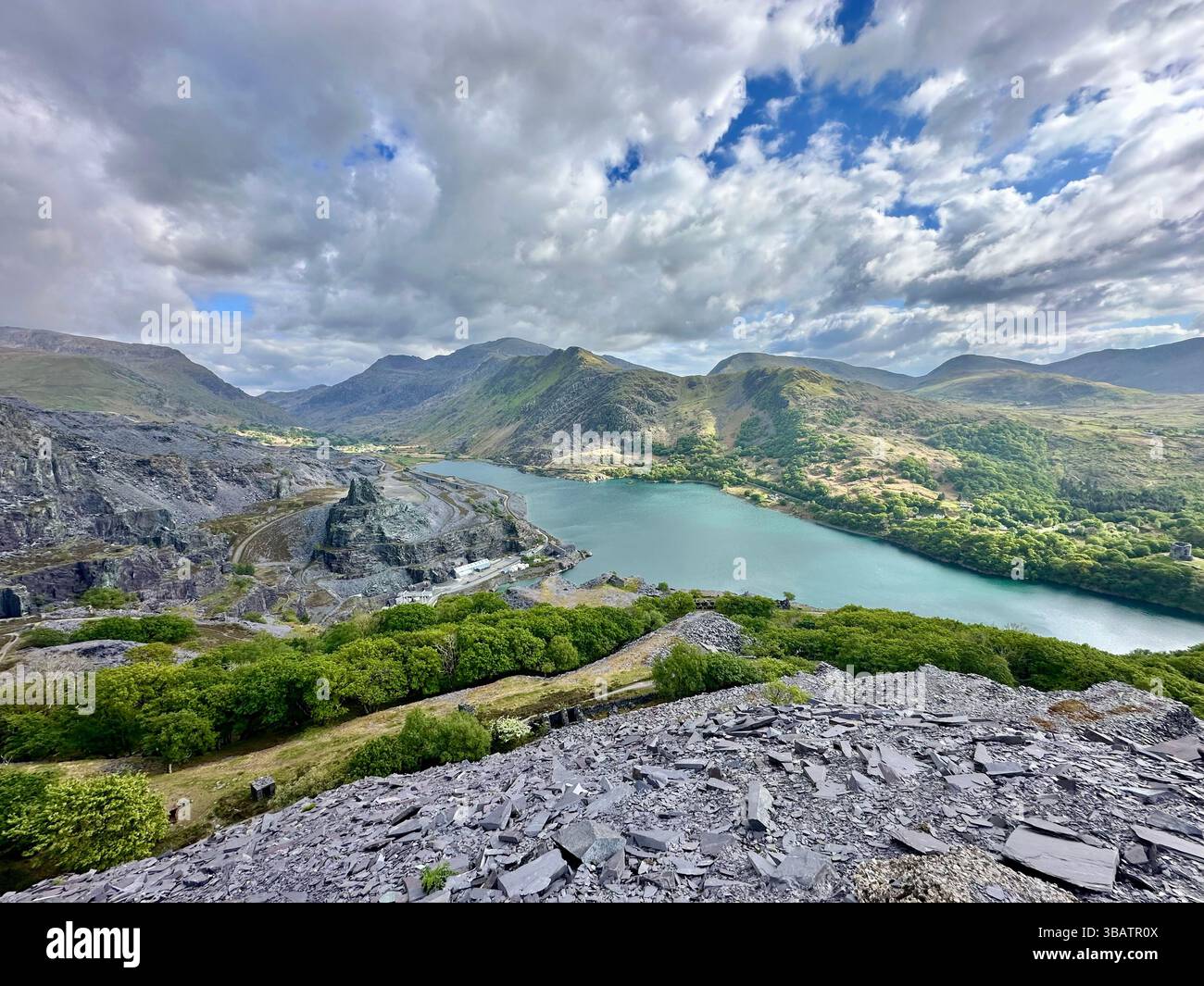Vista panoramica sopraelevata dalla cava Dinorwic che si affaccia su Llyn Paris con il suggestivo paesaggio montano di Snowdonia sullo sfondo. Giorno luminoso. - Immagine stock catturata con smartphone