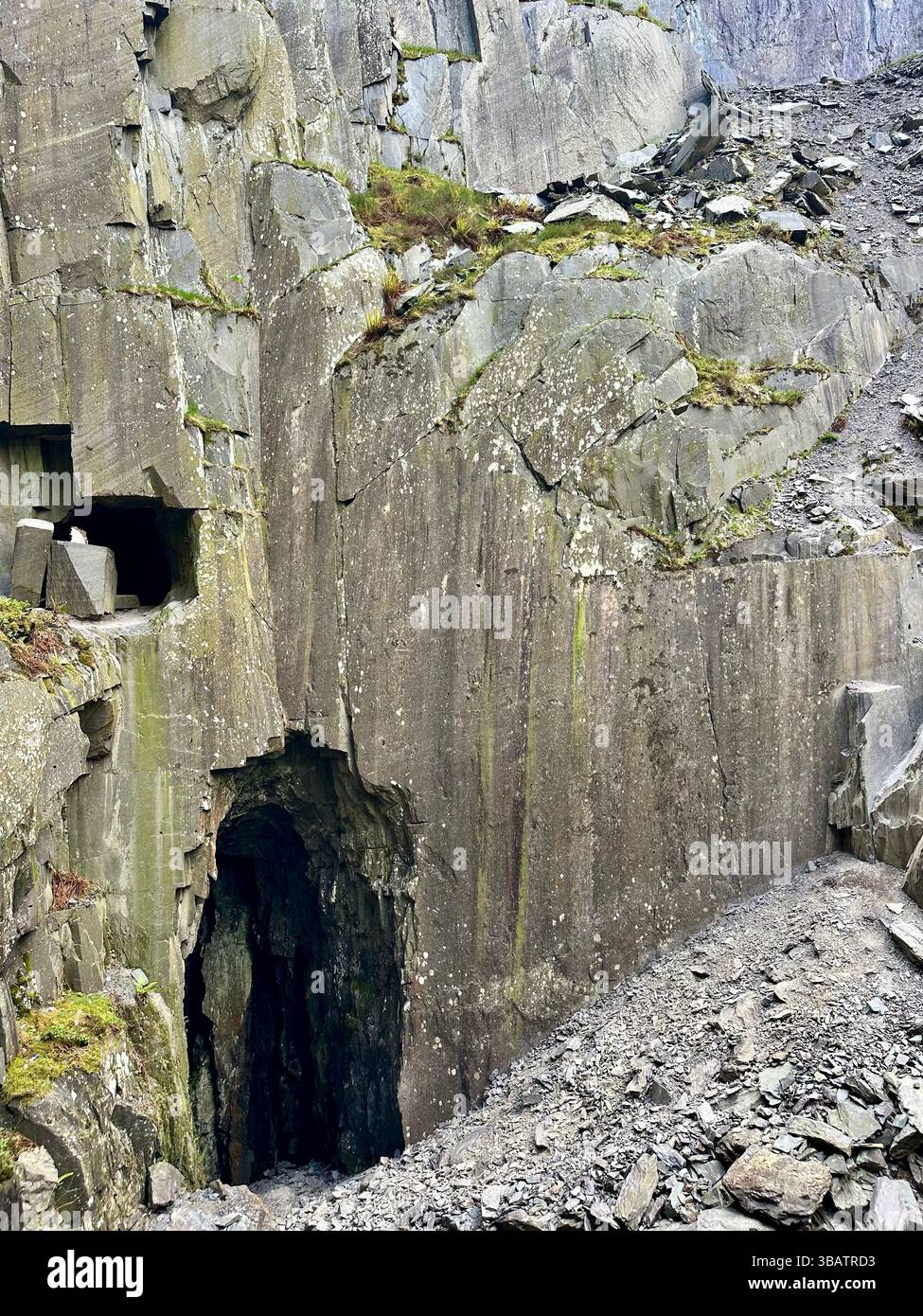 Parete in ardesia con muschio, sezioni ritagliate e detriti di ardesia sul terreno al centro della cava Dinorwic, Llanberis, Galles del Nord. - Immagine stock catturata con smartphone