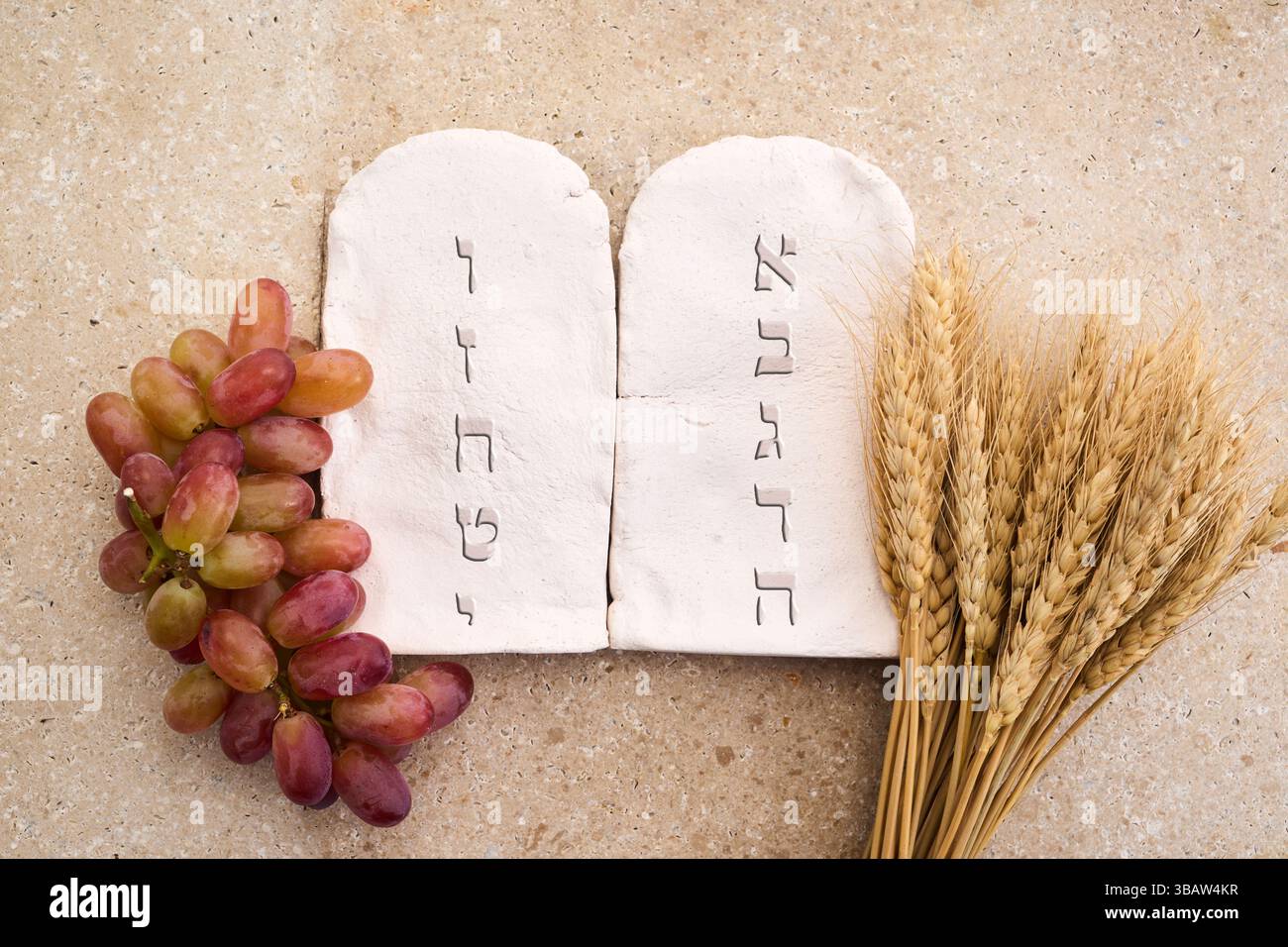 Happy Shavuot. Due pietre con dieci comandamenti in ebraico antico, cereali, latte e formaggio Foto Stock