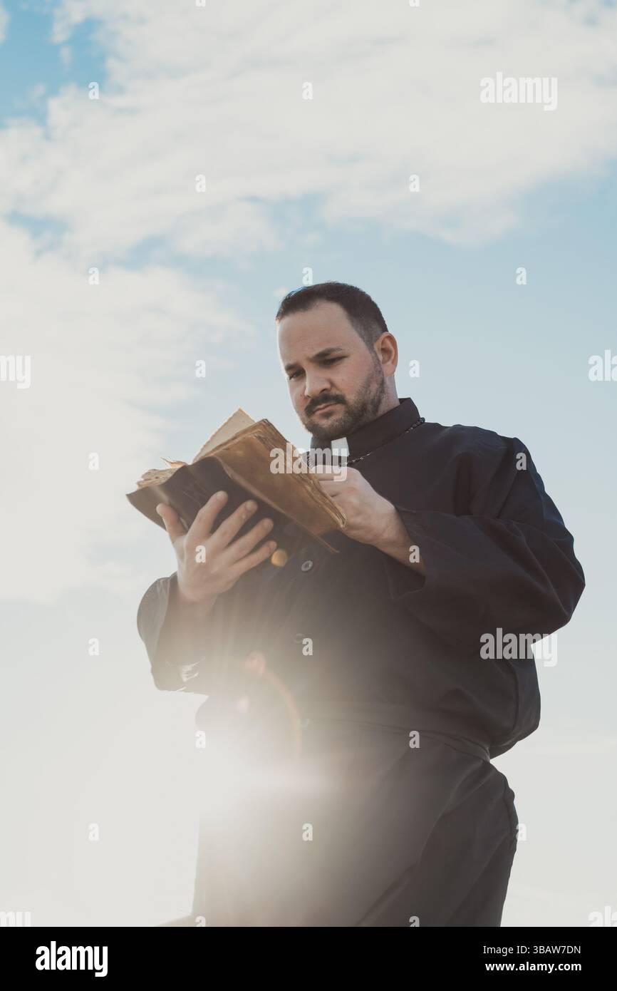 Il sole colpisce il sacerdote leggendo le parole di Dio Foto Stock