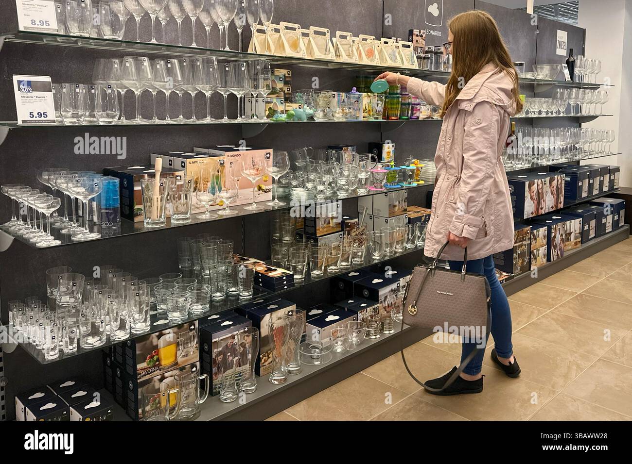 24.04.2024, Germania, Berlino, Berlino - Una giovane donna guarda i vetrai nel reparto di articoli per la casa di un grande magazzino. 00S240424D297CAROEX.JPG Foto Stock